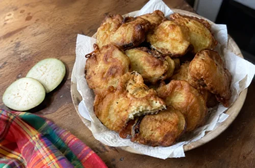 Beignets de bringelle 974 croustillants dans une assiette, avec des tranches d'aubergine crue à côté