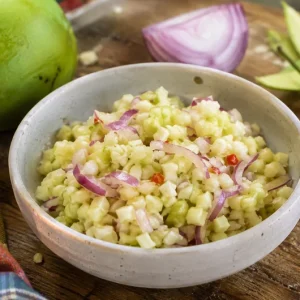 Rougail mangue verte fraîchement préparé dans un bol, avec oignon rouge et piment