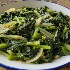 Fricassée de brèdes chouchou dans une assiette, feuilles et tiges sautées à l'ail et à l'oignon