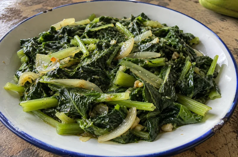 Fricassée de brèdes chouchou dans une assiette, feuilles et tiges sautées à l'ail et à l'oignon
