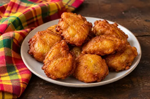 Assiette de beignets de banane réunionnais dorés, à côté d'un torchon madras