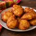 Assiette de beignets de banane réunionnais dorés, à côté d'un torchon madras