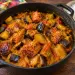 Marmite en fonte de boucané bringelle : morceaux de boucané dorés et cubes d'aubergine avec leur peau, fondus dans une sauce tomate au curcuma, à côté d'un bol de riz blanc