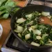 Brèdes chou de Chine sautées à l'ail et à l'oignon dans une sauteuse en fonte sur la gazinière, tiges blanches et feuilles vertes, à côté d'une botte de pak choï et d'un bol de riz