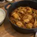 Marmite en fonte de poulet massalé réunionnais, cuisses et pilons dans une sauce brune à la tomate et aux épices, sur un plan de travail à côté d'un bol de riz blanc