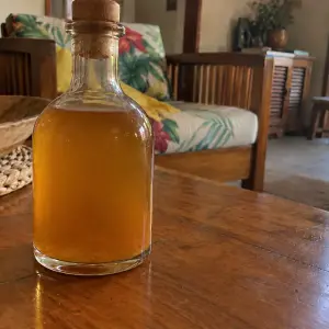 Bouteille de rhum arrangé Werther's Original couleur caramel doré, bouchée de liège, sur une table basse en bois dans un salon créole