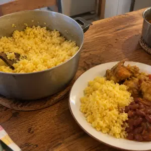 Marmite de riz maïs aux grains jaunes bien détachés, et assiette servie avec un cari et des grains de haricots rouges