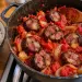 Marmite en fonte de rougail zandouille sur la gazinière : rondelles épaisses d'andouille fumée dans une sauce tomate aux oignons, à côté d'un bol de riz blanc