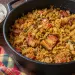 Marmite en fonte de cari ti jacques boucané : jacquier vert effiloché au curcuma, morceaux de boucané dorés, tomate et thym, à côté d'un bol de riz blanc